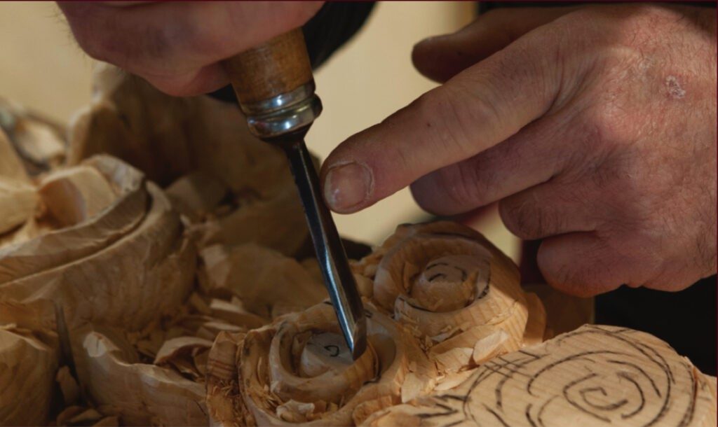 Hands carving wood with a chisel — conservation work at the Minster.