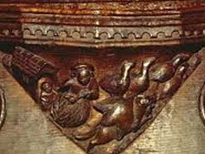 A carved misericord beneath a Minster choir-stall seat.