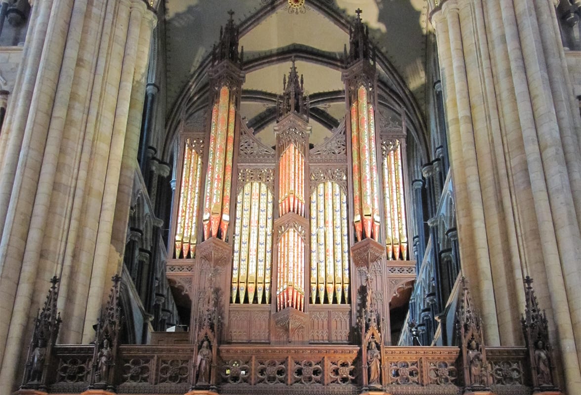 The Snetzler organ at Beverley Minster — painted pipes beneath Sir Gilbert Scott's carved screen, framed by the nave columns.