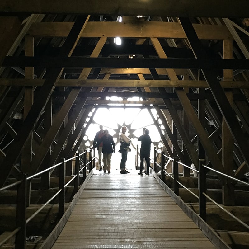 Visitors on a roof tour, crossing a walkway inside the Minster's timber roof structure.