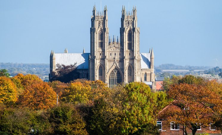 The west front of Beverley Minster across autumnal trees.